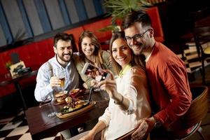 amigos jovens bonitos fazendo selfie e sorrindo enquanto jantava no restaurante foto