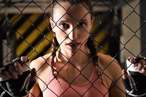 uma estagiária de artes marciais mistas se aquece dentro da gaiola do ringue, alongando as costas e as pernas. foto