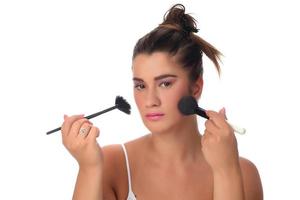 retrato de uma jovem aplicando maquiagem no rosto. isolado no fundo branco foto
