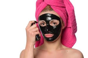 jovem mulher bonita com uma máscara para o rosto da lama negra terapêutica foto