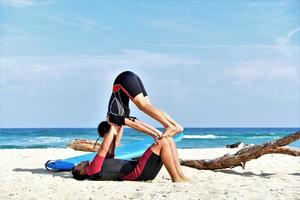 ajuste o casal desportivo praticando acro yoga com o parceiro juntos. apto casal desportivo praticando ioga acrobática juntos na praia foto