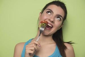 retrato de uma menina lúdica feliz comendo salada fresca de uma tigela foto