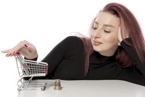 mulher feliz segurando cartões de crédito e um pequeno carrinho de compras vazio isolado no fundo branco foto