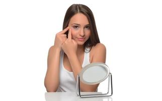 conceito de pele propensa a acne. jovem olhando para o espelho em casa, verificando a pele do rosto foto