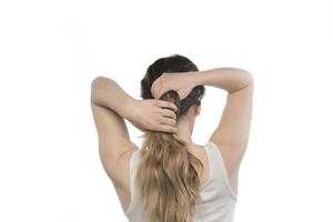 modelo feminino arrumando o cabelo dela. mulher amarrando o cabelo em um coque. foto