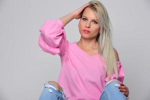 retrato de mulher jovem e bonita em camisa rosa bonita e jeans azul posando no estúdio. conceito de beleza, emoções, expressão facial, estilo de vida, moda, cultura jovem foto