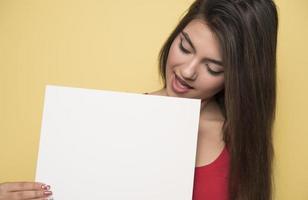 jovem mulher sorridente segurando uma folha de papel em branco para publicidade foto