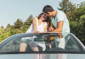 amigos se divertindo na viagem de carro ao redor do mundo. casal apaixonado com os braços para cima em um carro conversível. foto