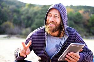 homem usando telefone celular enquanto relaxa na praia foto