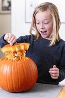 lindo menino loiro esculpindo abóbora com faca para o halloween. conceito de halloween foto