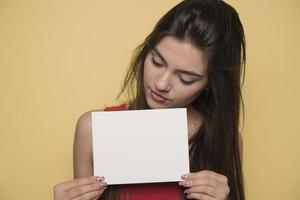 jovem mulher sorridente segurando uma folha de papel em branco para publicidade foto