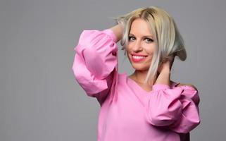 retrato de mulher jovem e bonita em camisa rosa bonita e jeans azul posando no estúdio. conceito de beleza, emoções, expressão facial, estilo de vida, moda, cultura jovem foto