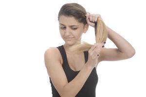 jovem mulher sorridente atraente segurando seu cabelo forte e conceito de xampu sorridente isolado no branco foto