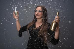 linda mulher comemorando o ano novo com confete e champanhe foto