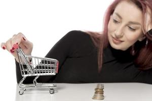 garota feliz segurando um pequeno carrinho de compras vazio isolado no fundo branco foto