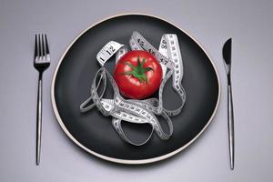 tomate e fita métrica no prato. o conceito de dieta. foto
