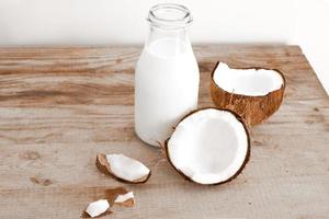 leite de coco fresco em garrafa de vidro, bebida saudável vegana não láctea. mesa de madeira, close-up. foto