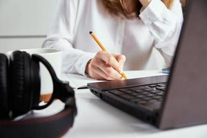 trabalho remoto. mulher faz anotações no caderno e usando laptop para estudo. foto