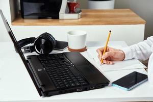 mulher faz anotações no caderno e usando laptop para estudo foto