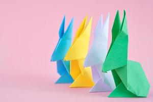 coelhos esater de origami colorido de papel em um fundo rosa foto