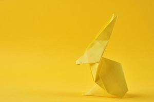 coelho esater de origami de papel em um fundo amarelo. conceito de celebração de páscoa