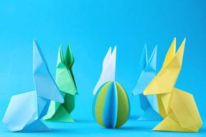 coelhos esater de papel origami e ovos coloridos em um fundo azul foto