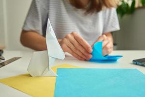 conceito de bricolage. mulher faz coelho de páscoa de origami de papel colorido. aulas de origami foto