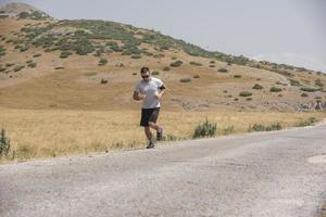 corredor de homem desportivo correndo no planalto da montanha no verão foto