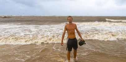 homem está na praia durante o furacão e gosta do méxico. foto