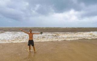 homem está na praia durante o furacão e gosta do méxico. foto