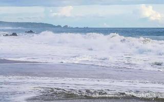grandes ondas de surfista e rochas na praia puerto escondido méxico. foto