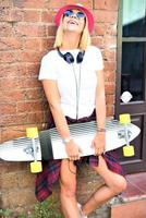 menina linda hipster com skate usando óculos escuros na cidade. foto