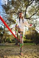 jovem equilibrando e pulando no slackline. mulher andando, pulando e se equilibrando na corda foto