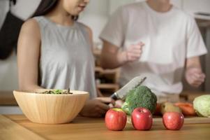 um jovem casal asiático gosta de cozinhar com vegetais saudáveis e ingredientes de frutas na cozinha em casa, conceito de estilo de vida saudável e bem-estar. foto