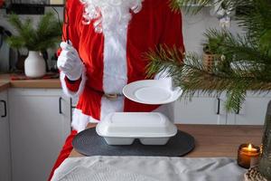 entrega de comida para recipientes de serviço doméstico nas mãos do papai noel coloca na mesa da cozinha e leva embora. pedido quente pronto, natal, restauração de feriados de ano novo. foto