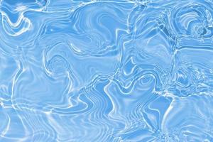 desfocar textura de superfície de água calma transparente de cor azul turva com salpicos e bolhas. fundo de natureza abstrata na moda. ondas de água na luz solar com cáusticos. água azul brilhando foto