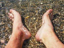 pés na água do mar límpida e transparente foto