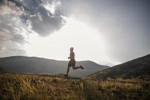 corredor de homem desportivo correndo no planalto da montanha no verão foto