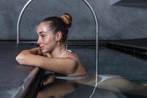 jovem mulher descansando na piscina limpa foto