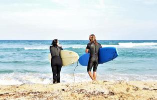 casal de surfistas esperando as ondas altas na praia - pessoas esportivas com pranchas de surf na praia - esporte radical e conceito de férias foto