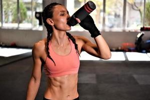 lutador feminino bebendo água e descansando após o treinamento. foto