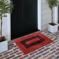 capacho de entrada de boas-vindas de design colocado no piso de tijolo sólido do lado de fora da porta de entrada com plantas foto