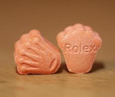 pílulas laranja com mdma ecstasy narcótico rolex close-up arte de fundo em impressão de alta qualidade foto