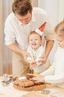 pai faz biscoitos de gengibre na cozinha com sua filhinha usando um chapéu de papai noel