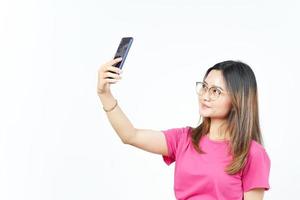 tire uma selfie usando o smartphone de uma linda mulher asiática isolada no fundo branco foto