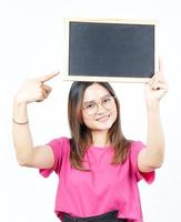 mostrando, apresentando e segurando o quadro-negro em branco da bela mulher asiática isolada no branco foto