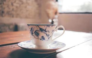 café preto em xícara de porcelana vintage em cima da mesa com estilo de filtro retrô foto