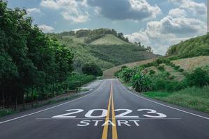 feliz ano novo 2023,2023 simboliza o início do ano novo. a carta começa o ano novo de 2023 na estrada na estrada da rota da natureza tem ecologia de ambiente de árvore ou conceito de papel de parede verde. foto