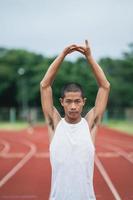 atletas esporte homem corredor vestindo roupas esportivas brancas para alongamento e aquecimento antes de praticar em uma pista de corrida em um estádio. conceito de esporte de corredor. foto