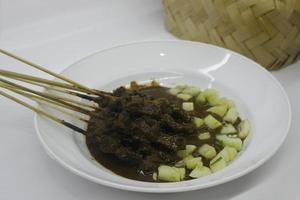 sate ou satay com molho de amendoim e pepino close-up foto